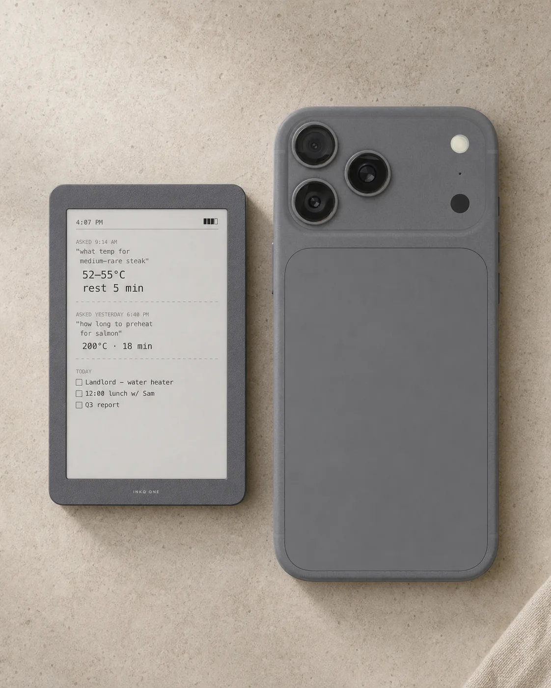 INKQ One 与一部手机并排放在浅色石灰岩桌面上的尺寸对比概念图